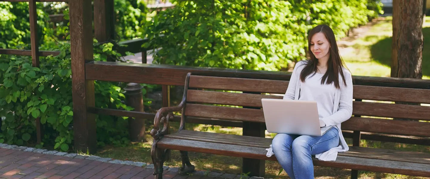 Woman setting on a bench with a laptop